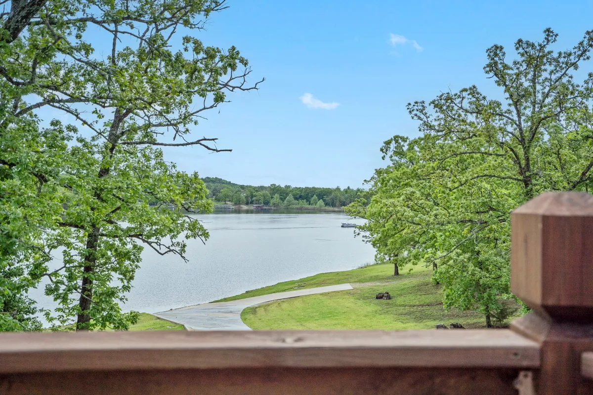 A peaceful pathway meanders through lush trees, leading down to a serene, calm lake. The setting radiates tranquility and invites leisurely walks, lakeside play, or quiet moments with a pet.