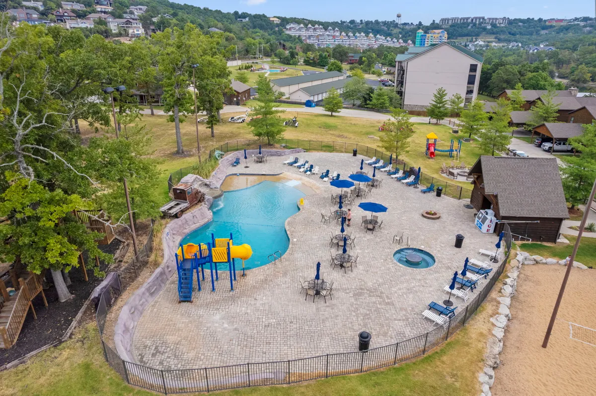This vibrant exterior shot showcases the resort’s outdoor pool, play area with slides, hot tub, lounge chairs, and a beach volleyball court. The area is bustling with energy and offers a glimpse of the fun, family-friendly amenities available to guests.