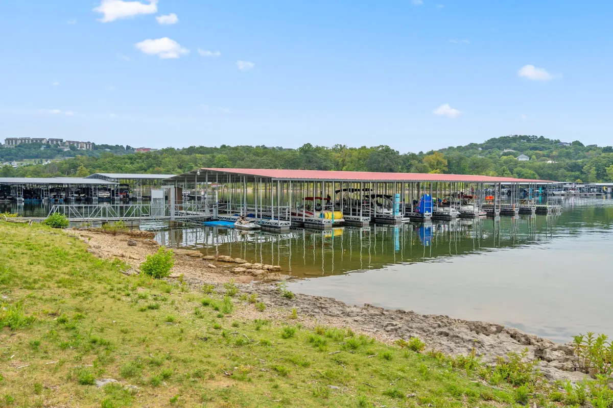 A peaceful shot of boat docks extending over the shimmering water surface, framed by green landscape. The scene suggests opportunities for boating, fishing, and other water sports, with a relaxed lakeside vibe.